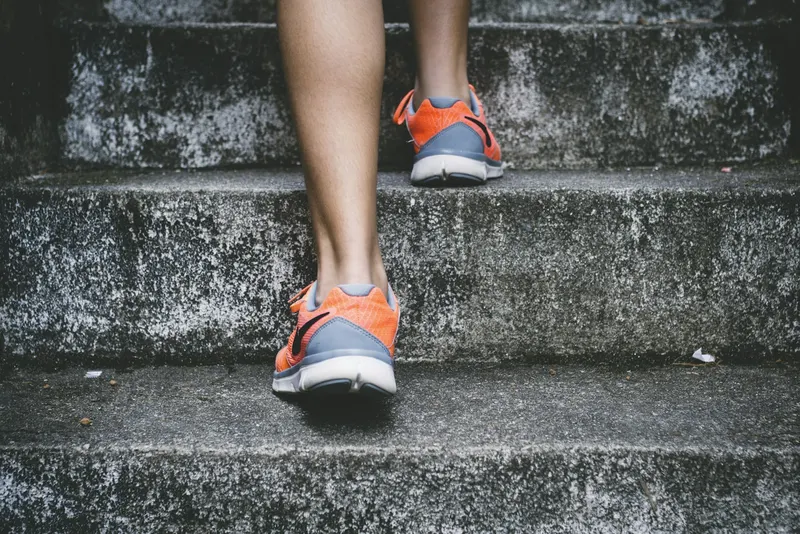 Runner's legs ascending concrete stairs during a workout
