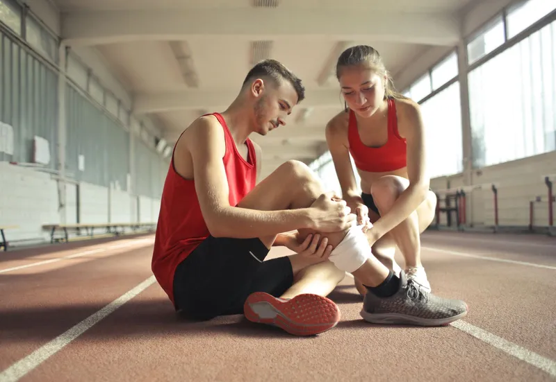 Injured athlete on a running track holding her lower leg in pain
